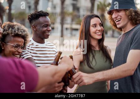 Es sieht aus, als ob eine Gruppe junger Menschen bei Sonnenuntergang mit Bier toasten. Stockfoto