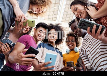 Low-Angle-Ansicht einer Gruppe junger Teenager, die Mobiltelefone halten. Konzept der Technik, Verbindung. Stockfoto
