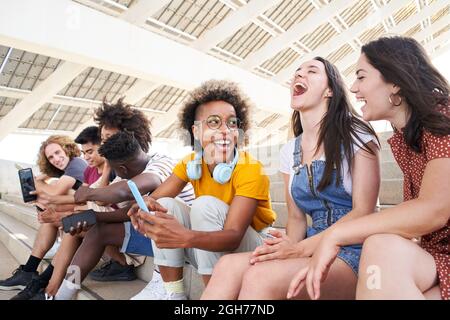 Multiethnische Gruppe junger Freunde, die Handys benutzen und Spaß haben. Stockfoto