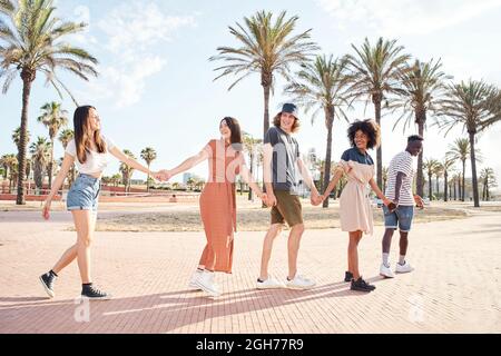 Junge Menschen gemischter Rassen gehen Hand in Hand durch eine Stadt. Konzept der Freundschaft, Sommer, Treffen mit Freunden. Stockfoto