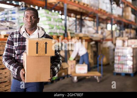 Mann, der Kartons im Lager trägt Stockfoto
