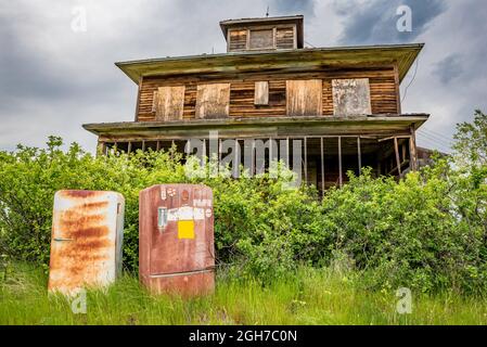 Zwei rostige Vintage-Kühlschränke, die vor einem alten Haus auf den Prärien aufgegeben wurden Stockfoto