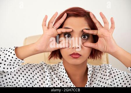 Gesicht einer müden jungen Geschäftsfrau, die versucht, ihre Augen offen zu halten Stockfoto