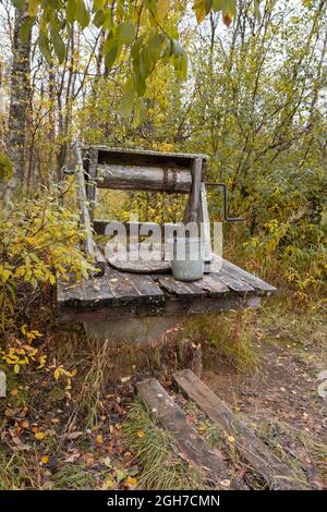 Alte hölzerne Wasserbrunnen mit Metalleimer im Herbstwald Stockfoto