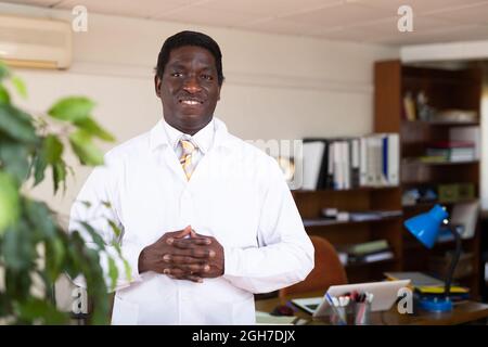 Professioneller afroamerikanischer Arzt, der im medizinischen Büro steht Stockfoto