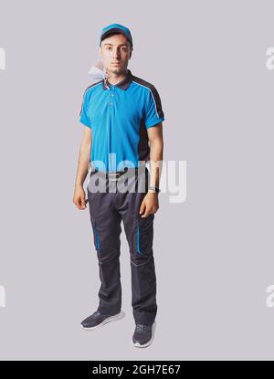 Das Foto in voller Länge eines Postboten in blauer Uniform und der Kappe, die die Digitaluhr trägt und an einem Ohr eine medizinische Maske trägt, sieht sehr ernst aus. Stockfoto