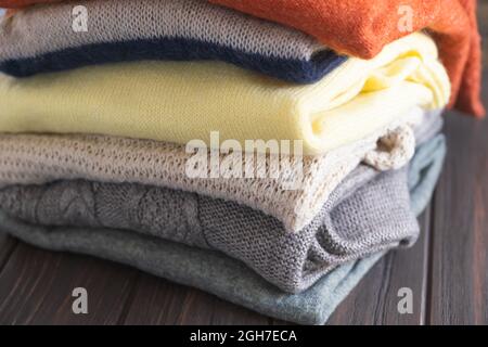 Kuschelige Pullover in Herbstfarben auf braunem Holzhintergrund. Stockfoto