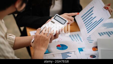 Das Geschäftsteam verwendet einen Rechner und einen Laptop, um die Zahlen auf seinem Schreibtisch in einem Büro zu berechnen. Stockfoto