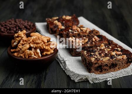 Schokoladenbrownie neben Walnüssen und Pralinen in Tontöpfen Stockfoto