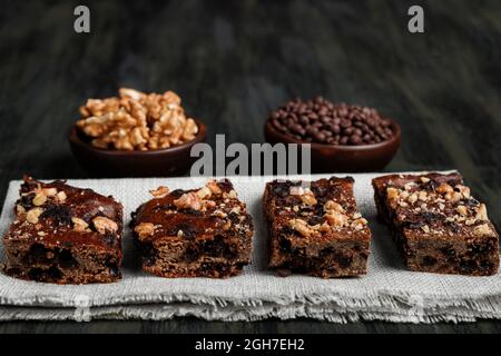 Schokoladenbrownie neben Walnüssen und Pralinen in Tontöpfen Stockfoto