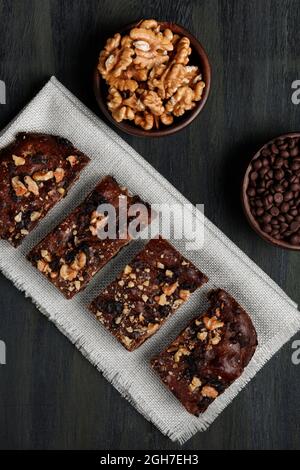 Schokoladenbrownie neben Walnüssen und Pralinen in Tontöpfen Stockfoto
