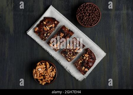 Schokoladenbrownie neben Walnüssen und Pralinen in Tontöpfen Stockfoto