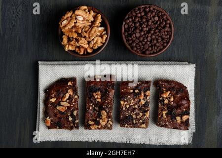 Schokoladenbrownie neben Walnüssen und Pralinen in Tontöpfen Stockfoto