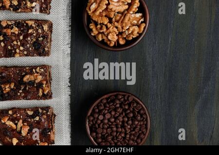 Stücke von Schokolade Brownie neben Walnüssen und Schokolade in Tontöpfen Stockfoto