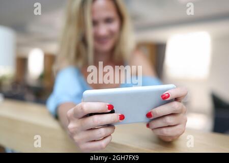 Lächelnde Frau mit Smartphone. Installation der Telefon-App Stockfoto