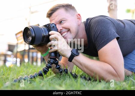Junger männlicher Fotograf fotografiert auf Stativ in Nahaufnahme der Straße Stockfoto