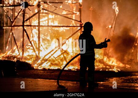 Ein Feuerwehrmann kontrolliert das städtische Feuer von La Falla, das in der Nacht von La Crema auf der Plaza del Ayuntamiento in Valencia brennt. La Crema ('verbrannt') ist der Akt des Feuers auf Karton- oder Holzdenkmäler (in diesem Fall die Fallas) während der Feierlichkeiten in verschiedenen Städten der Valencianischen Gemeinschaft (Spanien). Mit der Verbrennung der Denkmäler markiert es das Ende des Festivals. Die Fallas, das berühmteste Fest in Valencia, wird vom 1. Bis 5. September 2021 mit Einschränkungen aufgrund der durch Covid19 verursachten Pandemie gefeiert. (Foto von Xisco Navarro/SOPA Images/Sipa USA) Stockfoto