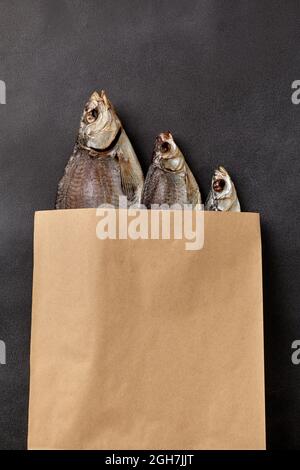 Drei gesalzene, luftgetrocknete Fische in einem Kraftpapier-Verpackungsbeutel Stockfoto