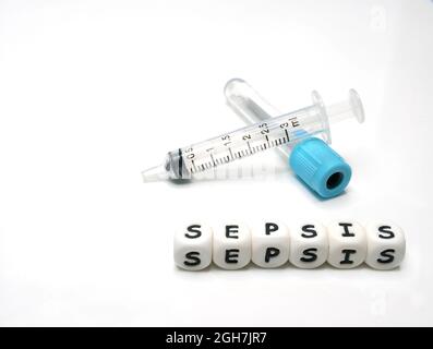 Reagenzglas und Spritze zur Entnahme von Blutproben zur diagnostischen Untersuchung und Silikonbuchstaben mit dem Wort „Sepsis“ Stockfoto