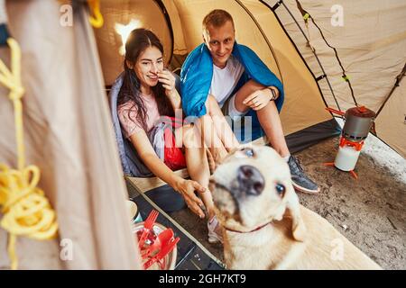 Glückliches Paar, das Spaß mit Hund im Lager hat Stockfoto