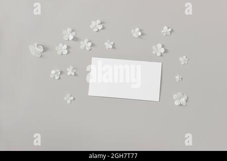 Moody feminine Hochzeit, Geburtstag Mockup Szene. Nahaufnahme einer leeren Visitenkarte aus Papier, Einladung auf grauem Tischhintergrund. Dekoratives Blumenmuster von Stockfoto