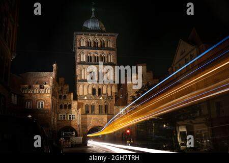 Leichte Spuren eines Busses, der nachts durch den Burgtor-Turm von Lübeck fährt, historisches Backsteingebäude der ehemaligen Stadtumschließungsmauer im ol Stockfoto