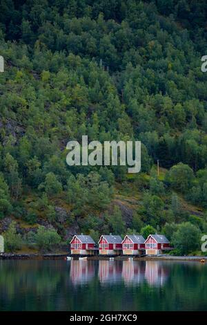 Reihe von vier traditionellen roten Holzhäusern am Fjordwasser in Flam, Norwegen, Europa Stockfoto