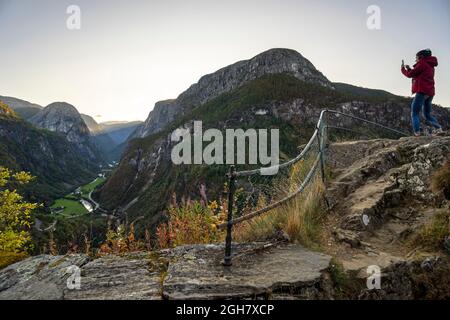 Junge Frau, die Landschaftsaufnahmen mit ihrem Smartphone in Stalheim, Norwegen, Europa macht Stockfoto