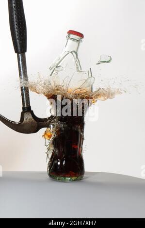 Stop Motion Hochgeschwindigkeitsfotografie eines Hammers, der eine Glas-Sodaflasche trifft und zerbricht Stockfoto