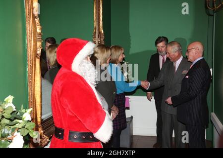 Dumfries House, Ayrshire, Schottland, Großbritannien. S.H. Prinz Charles trifft am 21. Dezember 2016 Mitarbeiter und den Weihnachtsmann bei einem Besuch im Dumfries House. Prinz Charles wird flankiert von seiner Hilfe Michael Fawcett (links von Prinz Charles) und Kenneth Dunsmuir (Geschäftsführer des Dumfries House und Botschafter bei der Prince's Foundation) Stockfoto