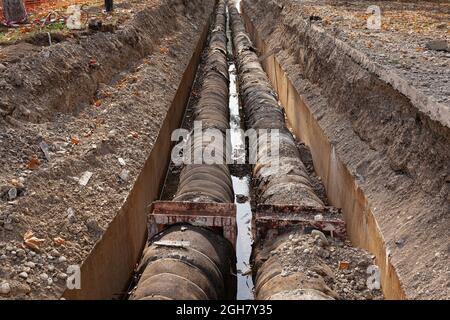 Große Rohre in Loch im Boden mit Schmutz bedeckt, Baustelle Stockfoto