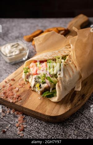 Döner Kebab, ein Shawarma in einer Grube aus frischem Gemüse und Fleisch. Mit großen Gewürzen. Restaurant serviert. Auf dunklem Hintergrund. Für Menüs und Werbung Stockfoto