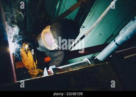 Junger Schweißer, der Schweißbrenner verwendet, während er vor Ort arbeitet Stockfoto