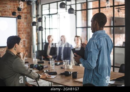 Männlicher Hacker präsentiert Ideen mit Kollegen im Kreativbüro Stockfoto