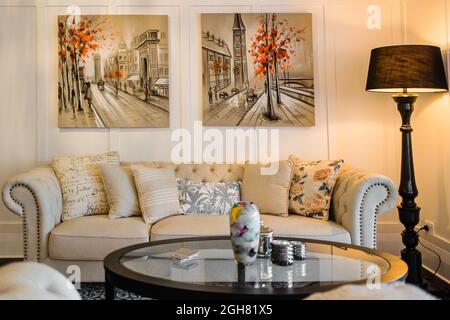 Großes und komfortables Wohnzimmer mit einem hellen Sofa und Gemälden an den Wänden Stockfoto