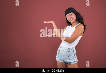 Junges chinesisches Mädchen mit Bandana und isoliertem T-Shirt, das auf die Seite zeigt und etwas zeigt. Stockfoto