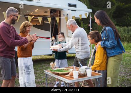 Multi-Generation-Familie feiert Geburtstag im Freien auf dem Campingplatz, Wohnwagen Urlaub Reise. Stockfoto