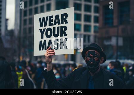 VANCOUVER, KANADA - 12. Apr 2021: Ein Mann hält das Schild „Wear your mask“ bei einem Stop-Asian-Hassprotest in Vancouver, Kanada Stockfoto