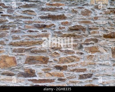 Alte natürliche braune Steinwand mit grauem Zementhintergrund Stockfoto