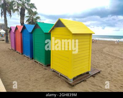 Holzhütten in verschiedenen Farben im Sand des Strandes von Oropesa del Mar an einem bewölkten Tag in Castellón, Spanien. Europa. Horizontale Fotografie. Stockfoto