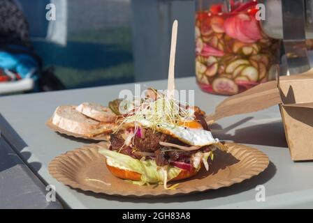 Rindfleisch-Tapa Burger, philippinischer Burger, Rindfleisch, Gemüse und Ei in einem Brötchen. Großes Glas mit eingelegtem Gemüse im Hintergrund. Asiatische Street Food mar Stockfoto