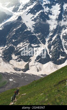 Eine Gruppe von Wanderern mit Rucksäcken wandern entlang einer Bergkette vor dem Hintergrund verschneiter Berge. Das Konzept der Reise zum Berg Stockfoto