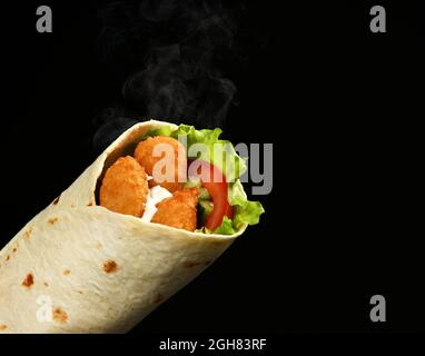 Klassische Tortilla Wrap Roll mit Nuggets und Gemüse, Tomaten, Salat auf schwarz Stockfoto