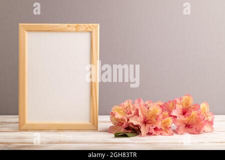 Holzrahmen mit rosa Azaleen-Blumen auf grauem pastellfarbenem Hintergrund. Seitenansicht, Kopierraum, Modell, Vorlage, Frühling, Sommer-Minimalismus-Konzept. Stockfoto