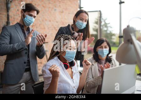 Junge und alte Geschäftsleute fühlen sich am Schreibtisch im Büro, bei der Zusammenarbeit und beim Coronavirus-Konzept erfreut. Stockfoto