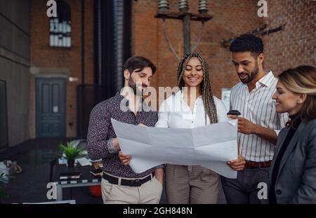 Fröhliche junge Geschäftsleute stehen und arbeiten im Büro, Zusammenarbeit und Brainstorming-Konzept. Stockfoto