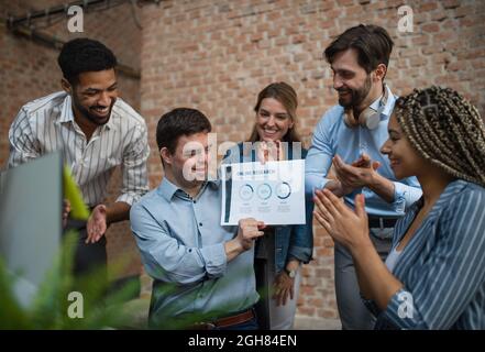 Happy Down Syndrom Mann mit Geschäftskollegen im Büro, soziale Inklusion und Kooperationskonzept. Stockfoto