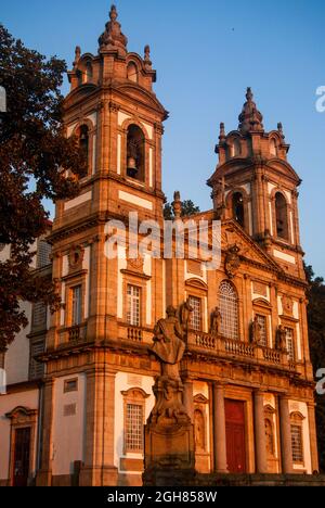 Schöne portugiesische Kirche und eine Statue werden bei Sonnenuntergang orange mit schönem klaren Himmel - Vertcal, Bom Jesus, Braga, Portugal Stockfoto