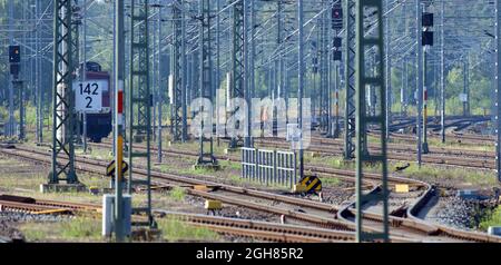 Magdeburg, Deutschland. September 2021. Ein Arbeiter in einer orangefarbenen, gut sichtbaren Weste geht auf dem Gelände des Hauptbahnhofs über die Gleise weg von einer E-Lokomotive der Deutschen Bahn. Bei einer Kundgebung der Deutschen Lokführer-Union (GDL) vor dem Bahnhof zeigten sich Mitglieder anderer Gewerkschaften solidarisch mit der GDL. Quelle: Soeren Stache/dpa-Zentralbild/dpa/Alamy Live News Stockfoto