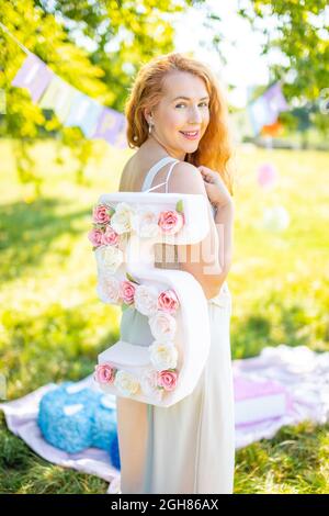 Schöne Frau mit Papiernummer mit Blumen in der Hand - Dekorationen mit eigenen Händen gemacht. Konzept für kleine Unternehmen. Stockfoto